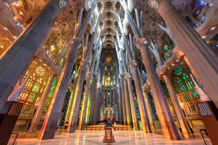 Infographic showing the interior of the Sagrada Familia in Barcelona with forest-like columns, colorful stained glass windows, central nave, main altar, and Gaudí’s architectural design.