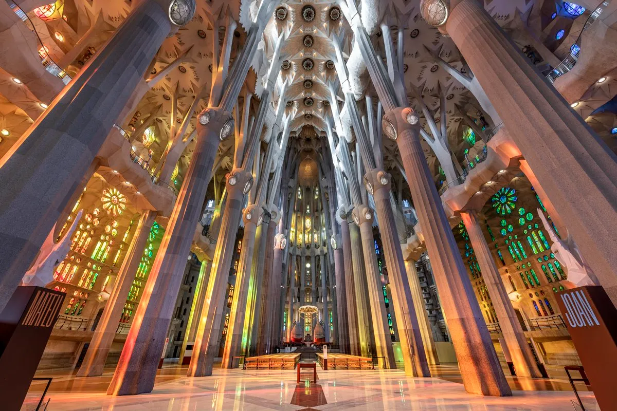 Infographic showing the interior of the Sagrada Familia in Barcelona with forest-like columns, colorful stained glass windows, central nave, main altar, and Gaudí’s architectural design.