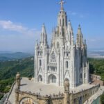 Infographic showing Tibidabo Barcelona 2026 travel guide with amusement park, Temple of the Sacred Heart, funicular transport, and panoramic views of Barcelona skyline and Mediterranean Sea from mountain summit.