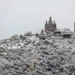 Tibidabo weather infographic showing seasonal temperatures, climate differences with Barcelona, wind and visibility conditions, and best time to visit Tibidabo mountain in 2026.